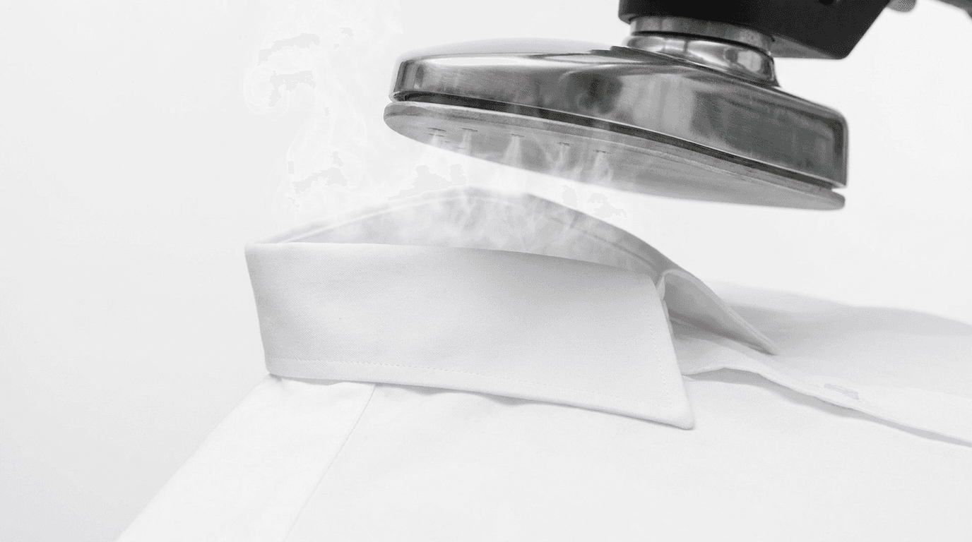 A steam press finishing the collar of a crisp white cotton shirt